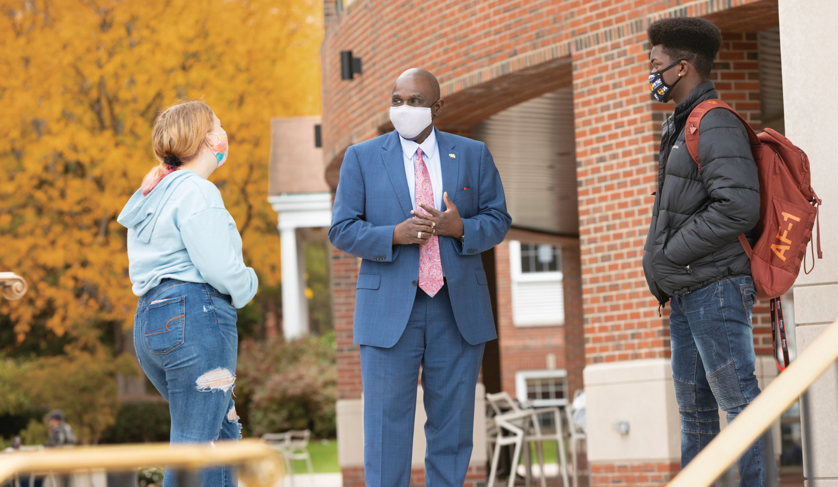 President Johnson standing and talking with two students on campus